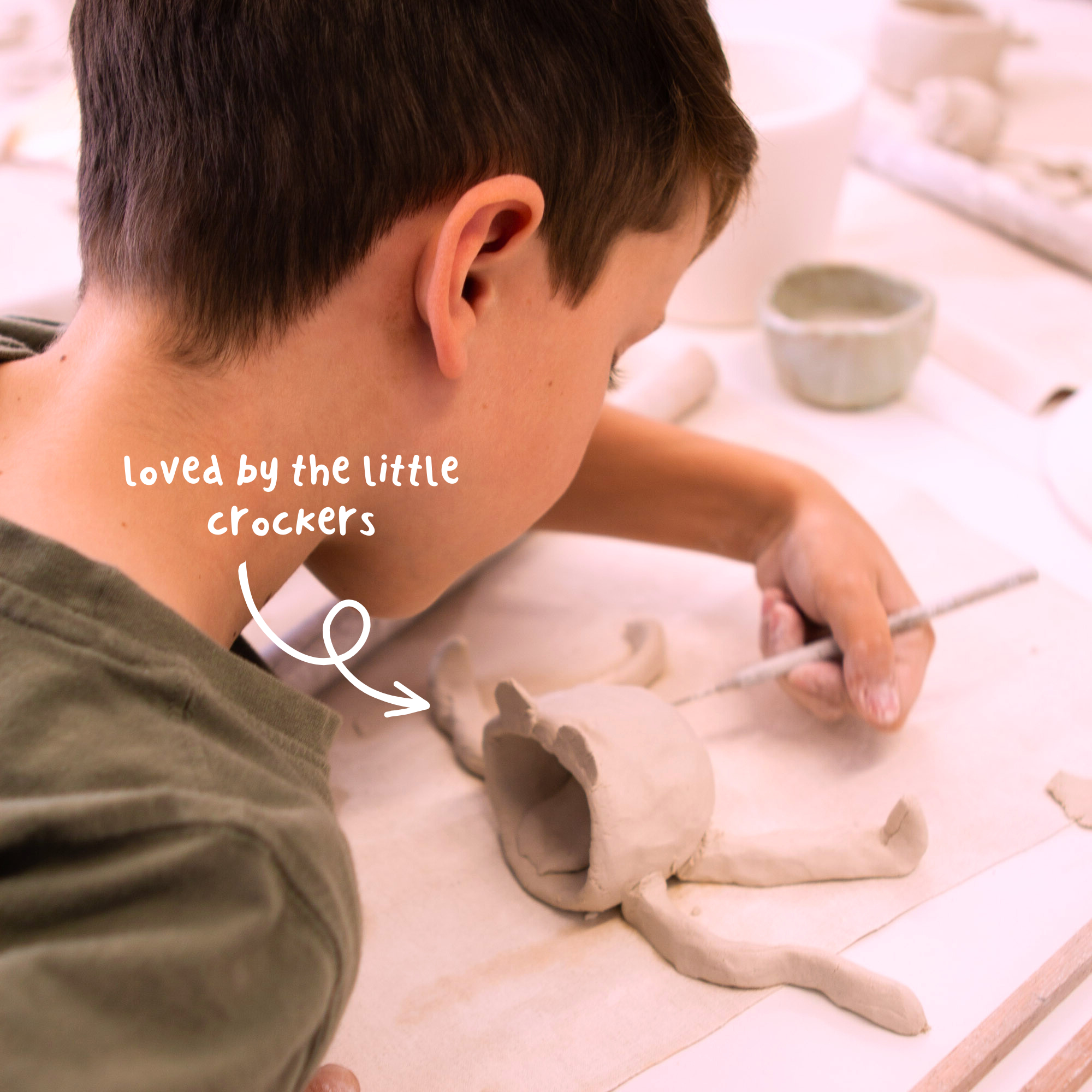 Child adding handle to hand-built ceramic mug