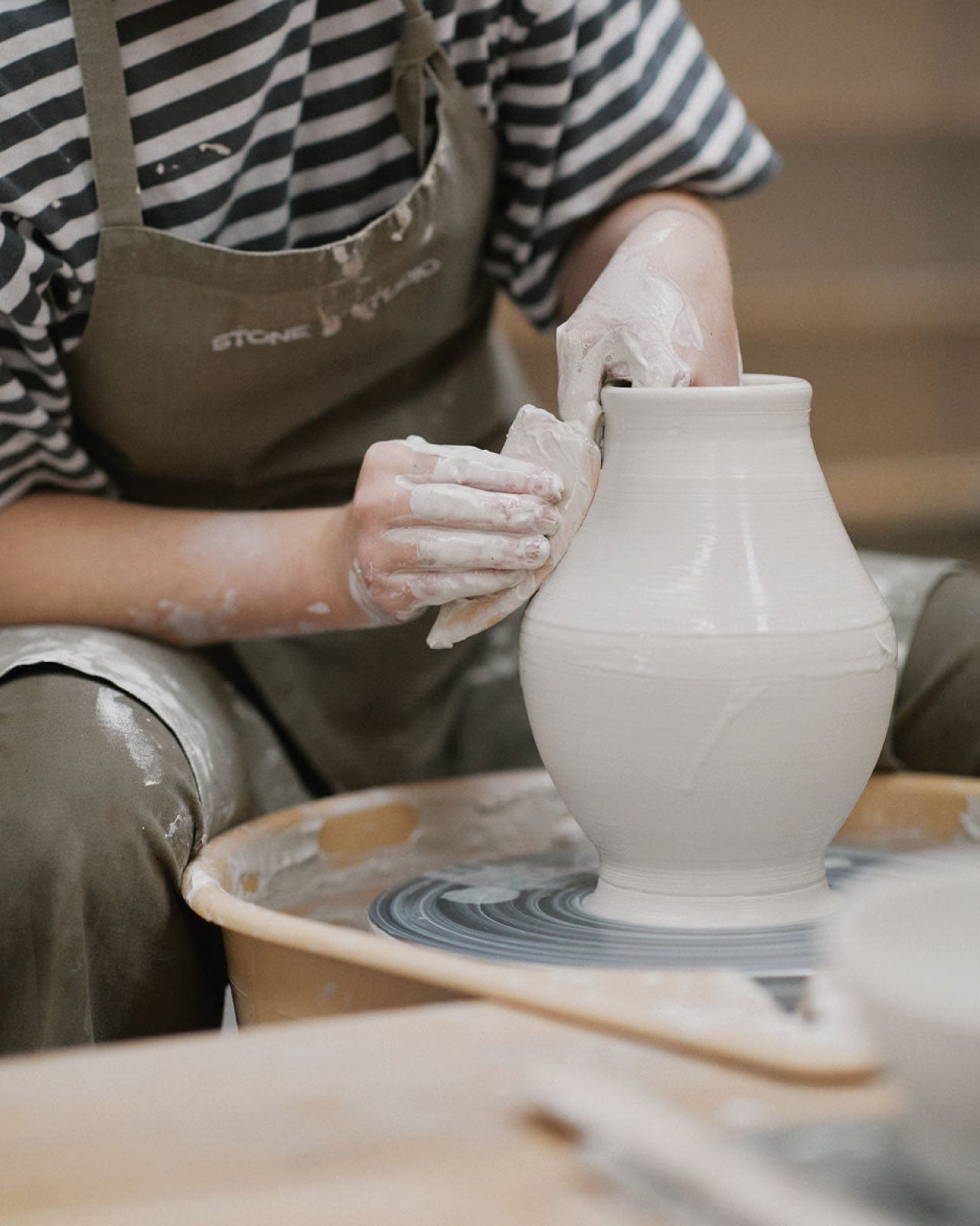 Student trimming bottom of wheel-thrown piece