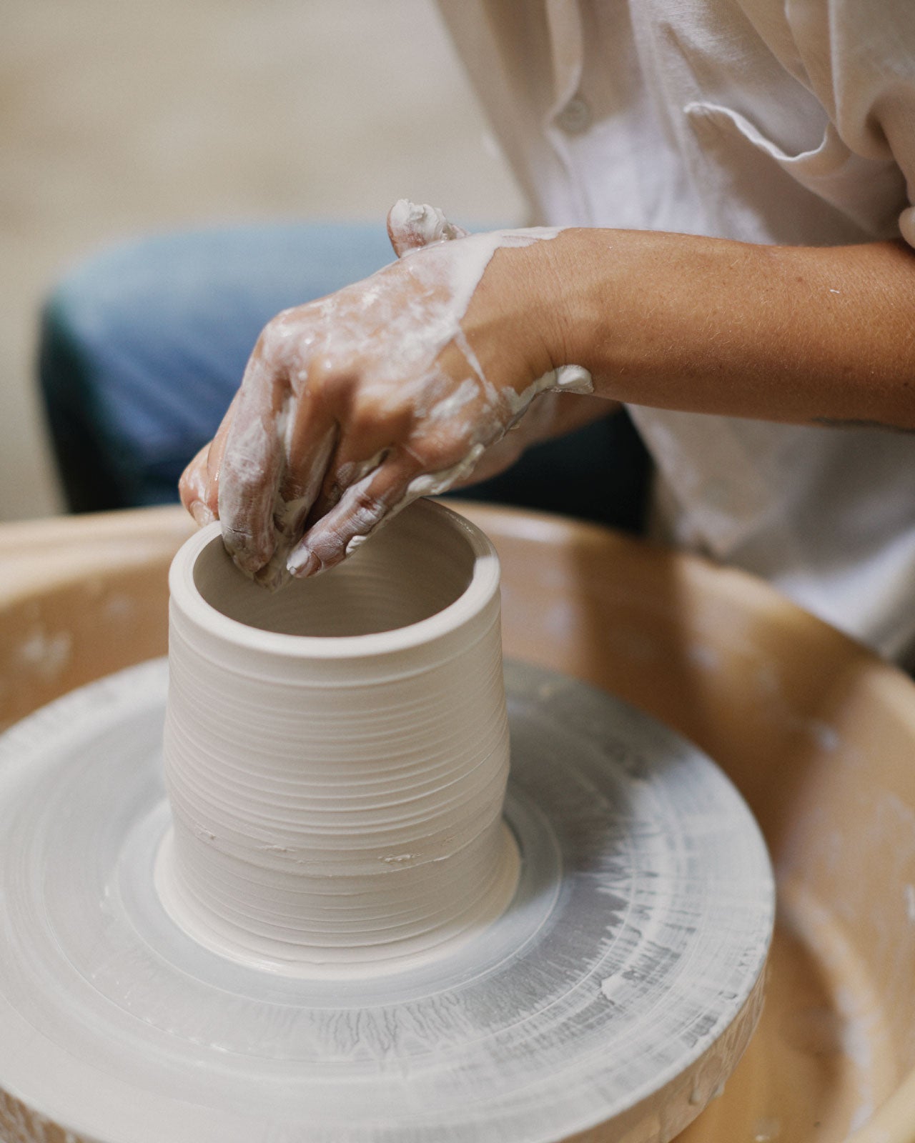 Participant shaping clay cylinder on pottery wheel