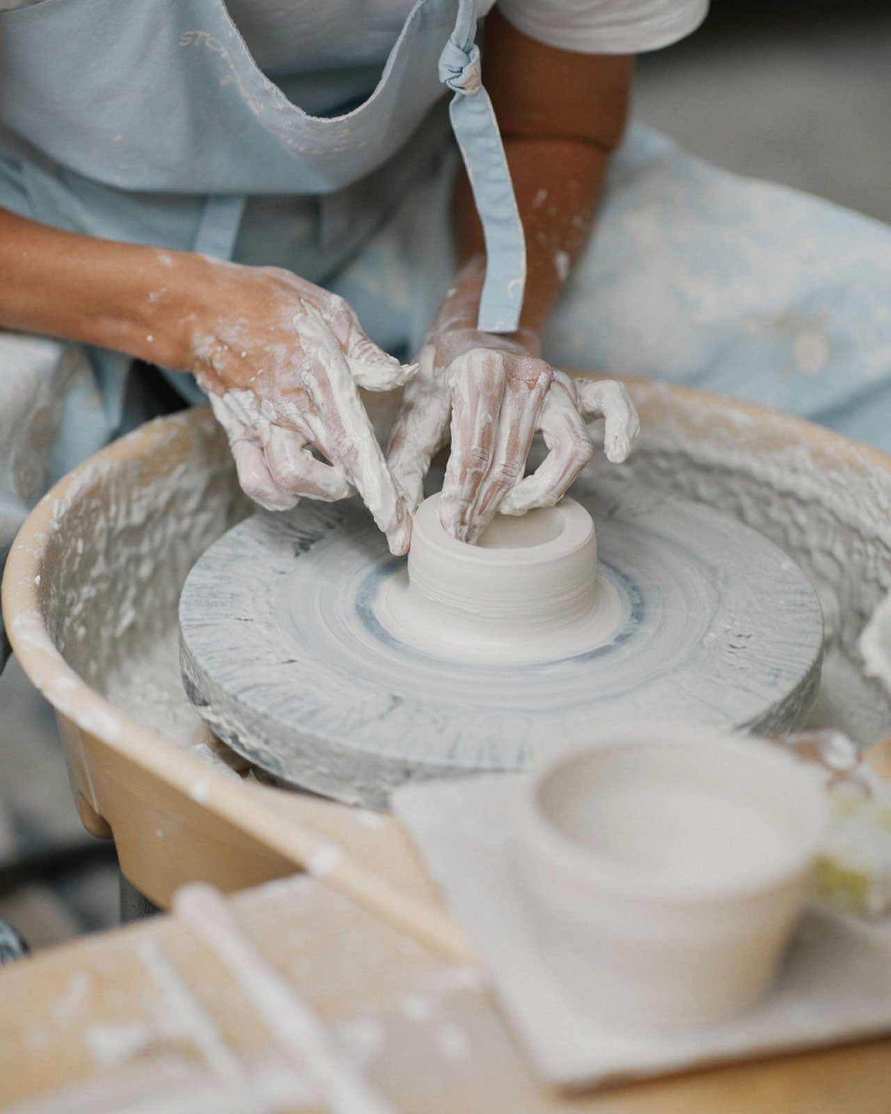 Student trimming bottom of wheel-thrown bowl