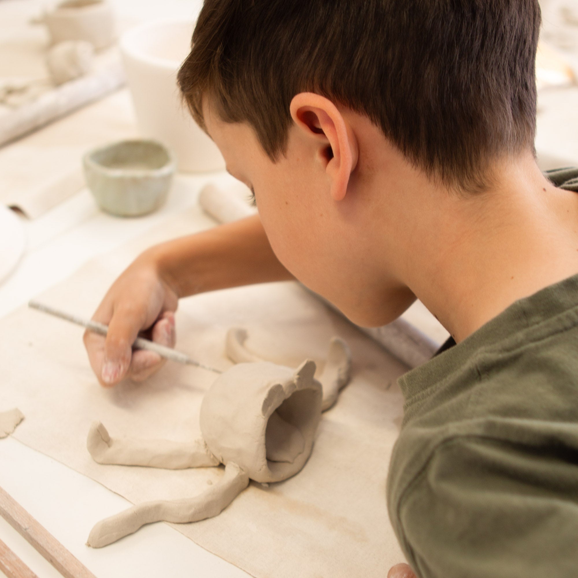 Child creating pinch pot with parent's guidance