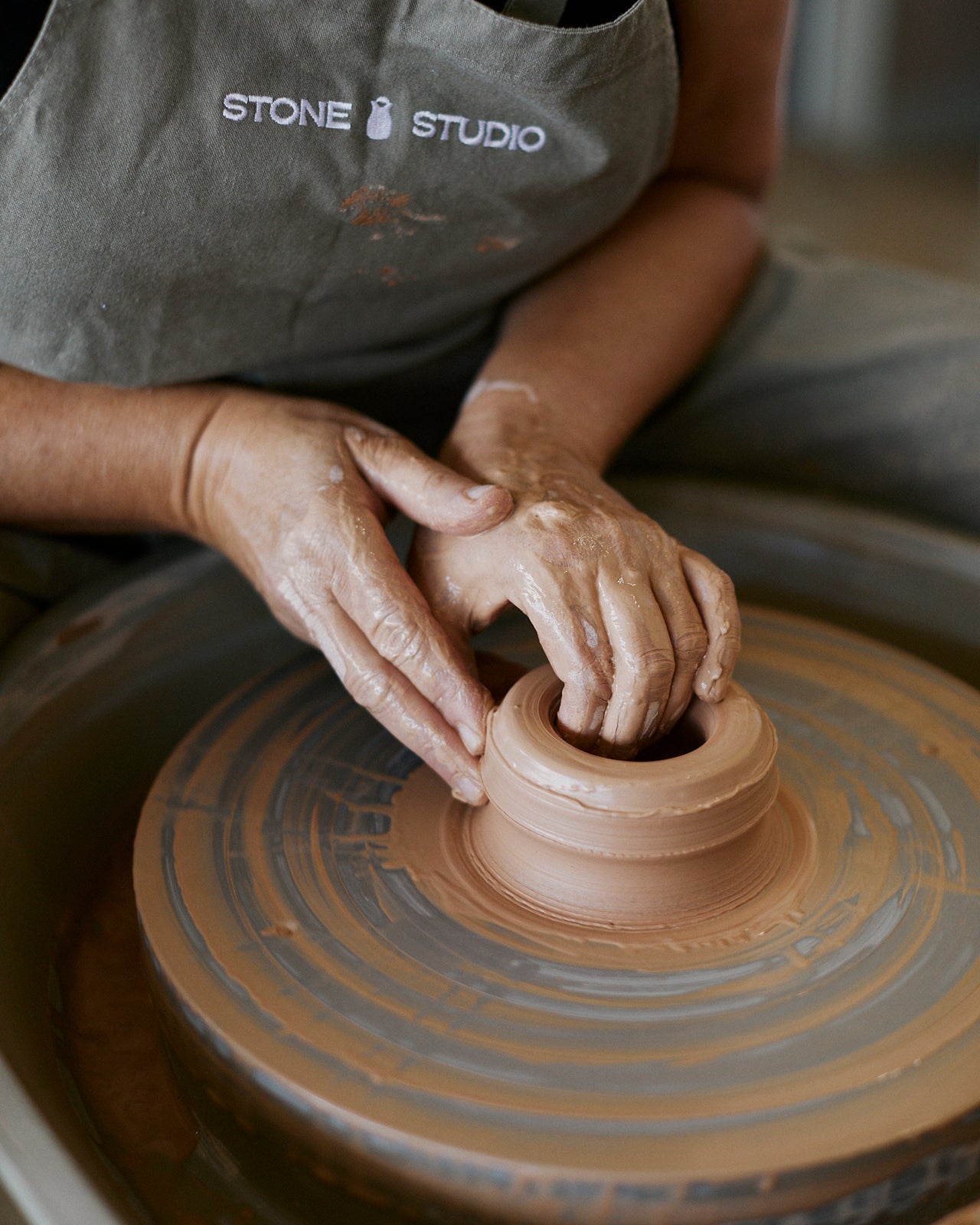 Student learning to center clay on pottery wheel