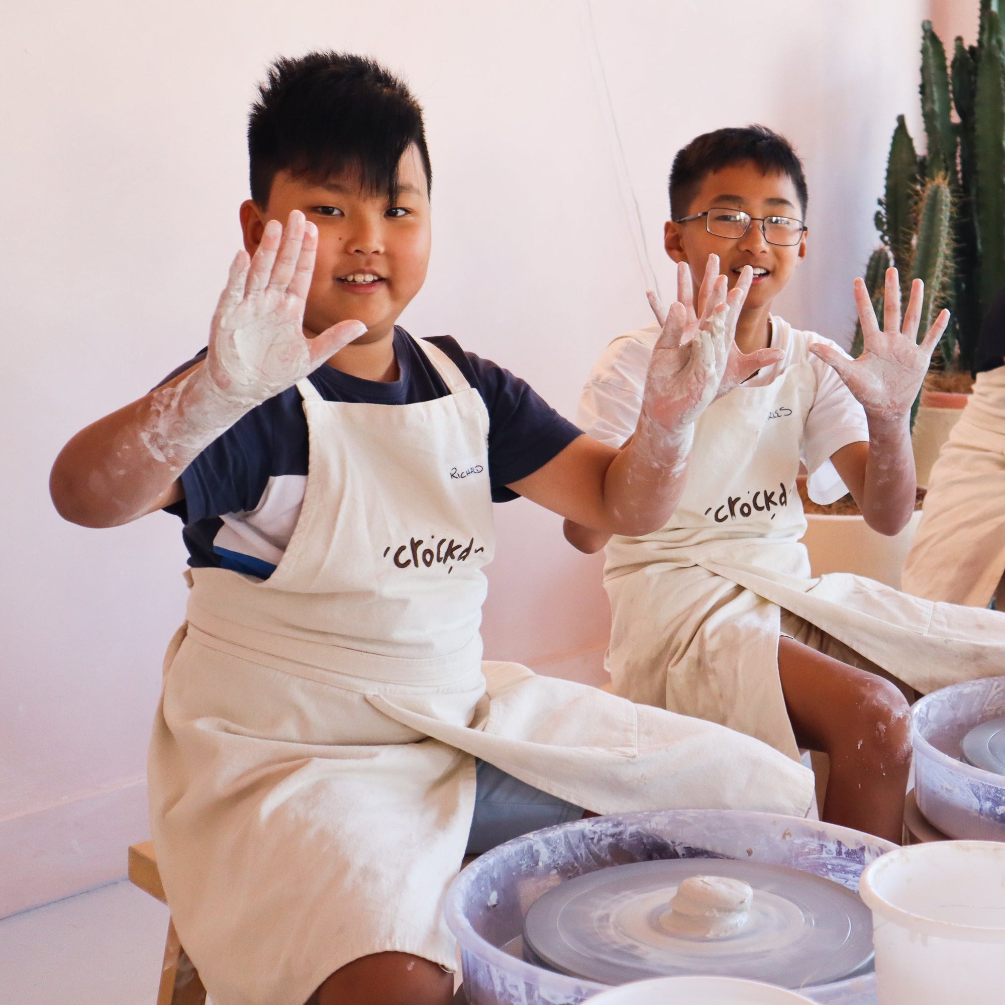 Instructor guiding child's hands on pottery wheel