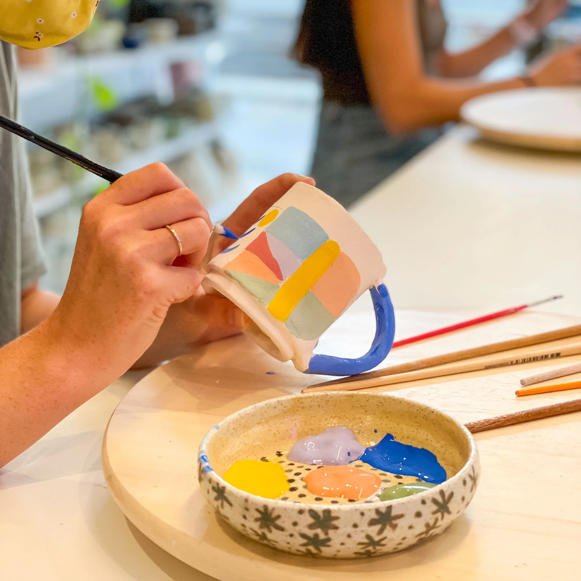 Instructor helping child on pottery wheel