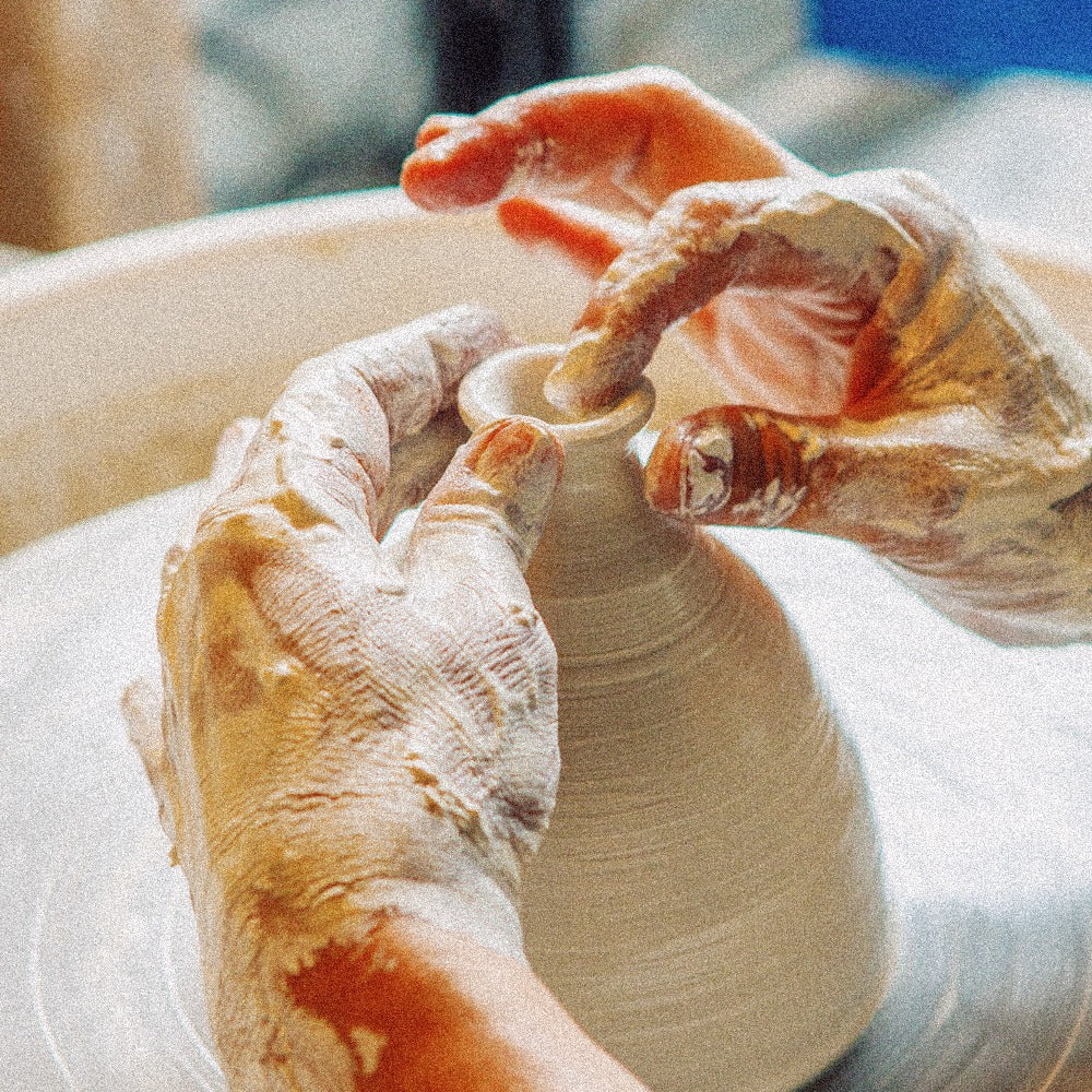 Student creating large form on pottery wheel