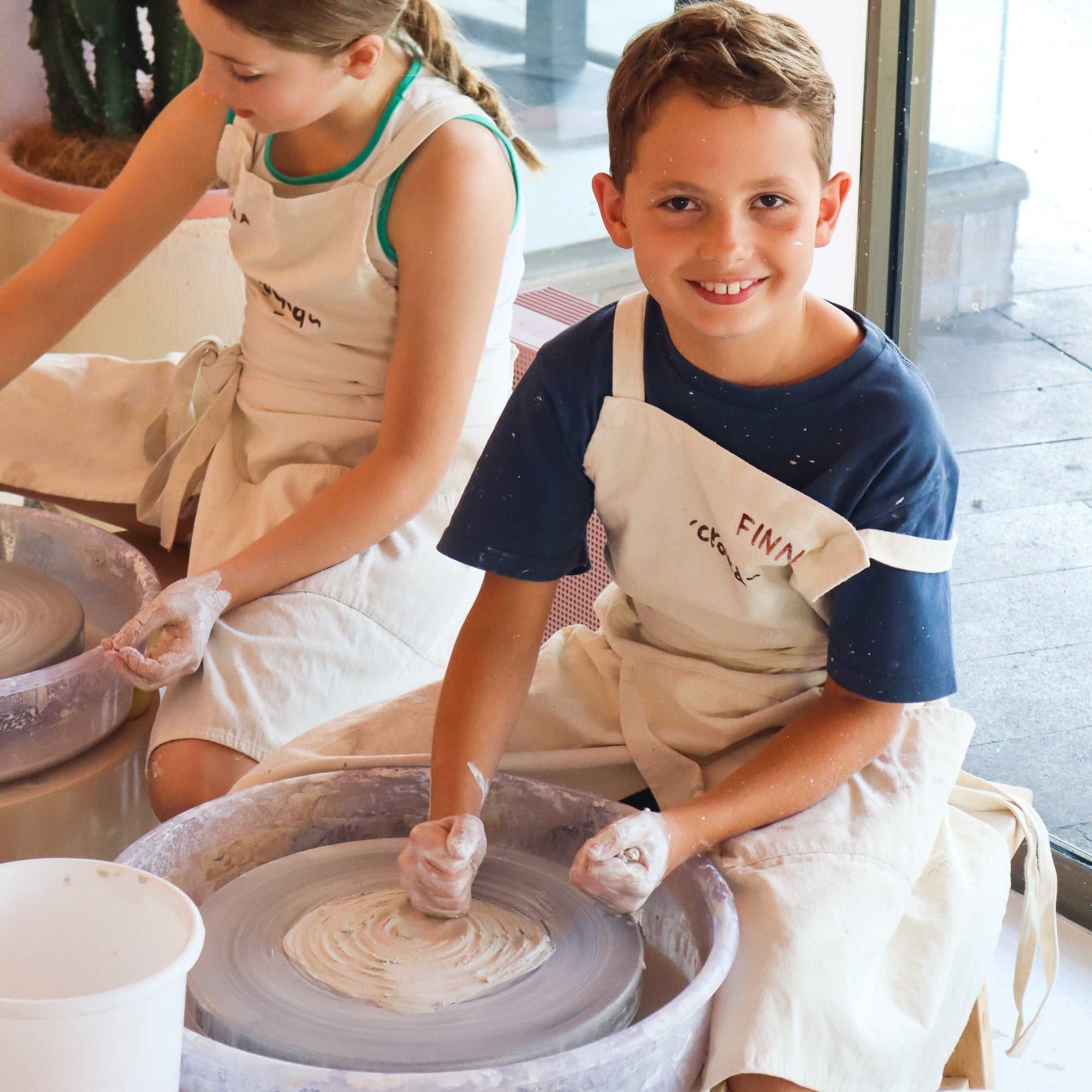 Various stages of kids' pottery projects on display