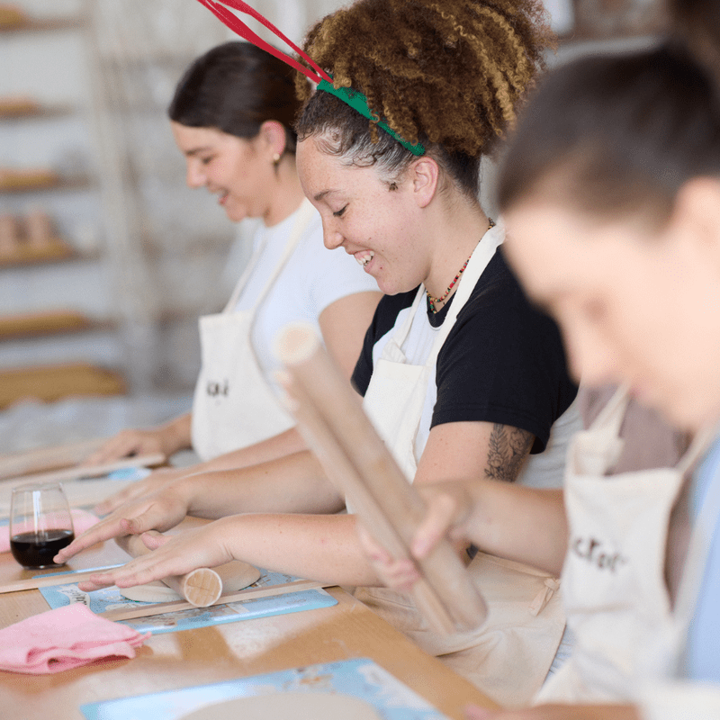People making and painting handmade ceramic Christmas ornaments during a pottery workshop.